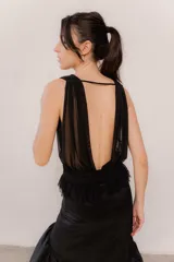Top de microtul negro con escote profundo, diseño sin mangas y espalda descubierta con ajuste regulable. Presenta una faja en la cintura con detalle de volados que aporta movimiento y una caída suave.