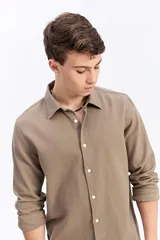 Camisa de manga larga color beige, de tejido texturado con cierre frontal de botones y cuello camisero clásico.