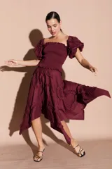 Falda midi asimétrica color bordó, con volados decorativos en espiral y cierre lateral.