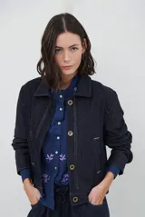 Chaqueta de pana color azul oscuro, con cuello camisero, cierre frontal con botones y bolsillos laterales. Diseño de corte recto y manga larga.