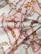 Pañuelo cuadrado de satén con estampado de cadenas y motivos ecuestres en tonos azul, blanco y dorado.