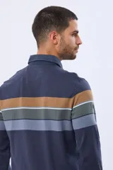 Remera polo de manga larga con diseño de rayas horizontales en tonos azul marino, marrón y gris. Presenta cuello camisero con cierre de botones y puños elásticos en las mangas.