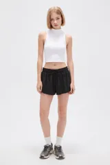 Short de poliéster color negro, de calce holgado y tiro alto, con cintura elástica y cordón ajustable.