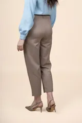 Pantalón de tiro alto color tostado, con diseño de pierna recta y largo al tobillo, con bolsillos laterales y cierre frontal con botón y cremallera.