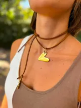 Collar tipo choker con doble tira de cuero marrón y dije en forma de corazón irregular color dorado.