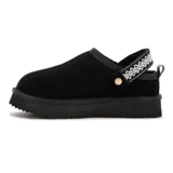 Zapato tipo zueco de gamuza negra con plataforma baja, costura frontal central y cinta decorativa bordada en blanco sobre el empeine.