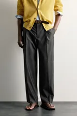 Pantalón de vestir gris con diseño de rayas sutiles, de corte relaxed fit, con pinzas delanteras y trabillas para cinturón.