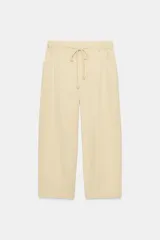 Pantalón de tiro medio confeccionado en mezcla de lyocell, con cintura elástica ajustable mediante cordones, bolsillos laterales y diseño de pierna ancha con sutil textura en espiga.