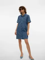 Vestido corto de denim en tono celeste claro, con cuello camisero, cierre frontal con botones metálicos, bolsillos con solapa en el pecho y mangas cortas con vuelta.