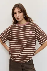 Remera de manga corta con diseño a rayas horizontales azules y blancas, cuello redondo en color tostado y parche bordado en el pecho.