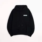 Hoodie negro de frisa con capucha y bolsillo canguro. Presenta un aplique rectangular en el pecho con texto en verde lima.