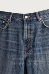 Jeans de denim de algodón en color azul con efecto desgastado, tiro medio y corte recto de ajuste holgado (loose fit). Cuenta con diseño clásico de cinco bolsillos y cierre frontal con cremallera y botón.