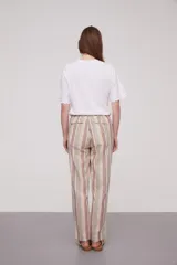 Pantalón babucha celeste con rayas verticales blancas, cintura elástica con cordón y detalle de borlas.