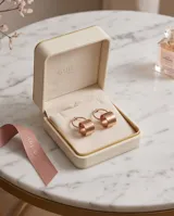 Caravanas colgantes de acero con diseño circular minimalista, compuestas por un aro superior y un cilindro inferior. Acabado en tono oro rosado.