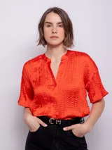Blusa de manga corta con escote en V, confeccionada en tela satinada con textura de pliegues horizontales.