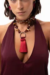 Collar corto con cadena de piedras naturales en tonos tierra y un dije central metálico en forma de herradura del que cuelgan tres borlas de seda en color bordó.
