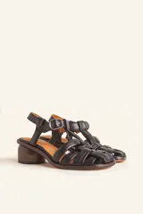 Sandalias de cuero color negro con diseño de tiras cruzadas tipo huarache, tira ajustable con hebilla metálica en el empeine y taco cilíndrico de madera.