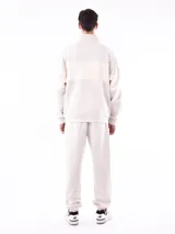 Buzo negro con cuello polo y cierre de cremallera parcial. Presenta una franja horizontal blanca en el pecho y mangas largas.