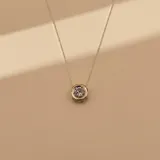 Collar de plata con cadena fina y dije redondo combinando plata y oro, engastado con una circonia central.