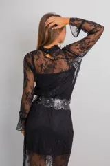 Conjunto de dos piezas compuesto por blusa de encaje semitransparente con cuello alto y mangas largas, y falda midi a juego. Ambas prendas incluyen visos interiores a tono. El diseño presenta un encaje floral delicado en color negro.