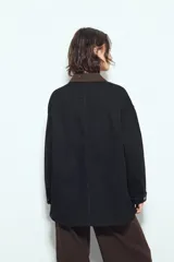 Sobrecamisa tipo Barn Jacket color marrón oscuro, de algodón con elastano, silueta relajada y estructura firme. Presenta cierre frontal con botones metálicos, cuello negro, bolsillos aplicados y pespuntes visibles.