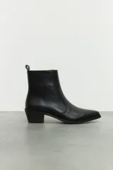 Bota corta de cuero sintético negro, con punta fina y cierre lateral metálico.