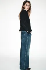 Blazer de corte entallado con cuello redondo, manga larga y hombreras. Presenta cierre frontal con botones dorados y una textura sutil en la tela.