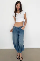 Jeans de tiro medio y diseño balloon, color azul denim con efecto lavado, cinco bolsillos, cierre frontal con cremallera y botón metálico, y bajos acabados en puño.