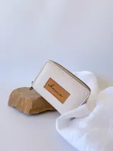 Billetera pequeña de cuero color crudo, con cierre metálico y monedero interno.