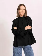 Camisa de lino color negro, con cuello mao, cierre frontal oculto y mangas largas fruncidas con puños amplios.