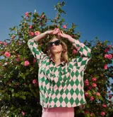 Camisa de corte holgado con cuello solapa y cierre frontal abotonado. Presenta un estampado geométrico de rombos en colores verde y rosado, con un bolsillo frontal en el pecho.