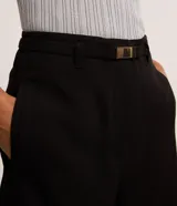 Short de sastrería color negro, de corte recto y cintura alta. Presenta trabillas para cinturón, un cinturón elástico con hebilla metálica y bolsillos decorativos en la parte posterior.
