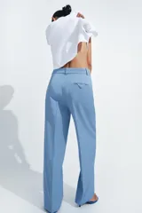 Pantalón de tiro medio con corte recto, confeccionado en mezcla de algodón. Presenta cintura con trabillas, bolsillos laterales ocultos en costura, raya planchada en el delantero y cierre frontal con cremallera, botón y ganchos metálicos.