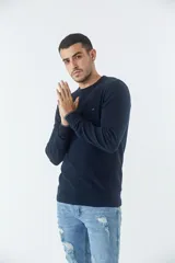Sweater de punto para hombre, color azul marino, con cuello redondo, mangas largas y textura en el tejido. Presenta un pequeño logo bordado en el pecho y puños acanalados.