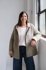 Tapado de paño con capucha, color beige, con cierre frontal, bolsillos laterales y puños vueltos en tono más claro.