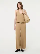 Mono color beige con escote halter, corte holgado, cinturón dorado y pantalones palazzo.