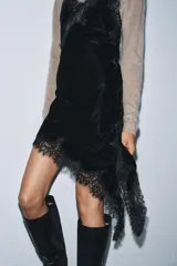 Vestido midi de terciopelo con escote en pico y tirantes finos. Presenta aplicaciones de encaje a tono y un diseño de bajo asimétrico.