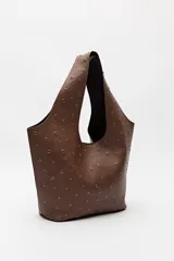 Bolso tipo tote negro de cuero sintético con micro tachas metálicas plateadas. Tiene asas integradas para llevar al hombro.
