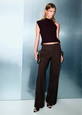 Pantalón de jean de tiro bajo y diseño wide leg, color marrón oscuro, con aplicación de strass en toda la superficie. Cuenta con cinco bolsillos, trabillas para cinto y cierre frontal con botón y cremallera.
