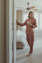 Pijama de satén elastizado color rosado, compuesto por una camisa de manga larga con botones frontales y vivos en contraste, y un pantalón recto con elástico y lazo en la cintura.