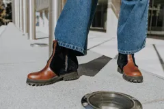 Botas de cuero marrón con la caña recubierta de corderito verde. Presentan una suela de plataforma tipo track en color beige y un tirador en la parte posterior para facilitar el calce.