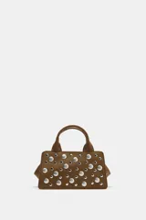 Bolso de mano estructurado color marrón, confeccionado en material tipo gamuza, con detalle de tachas metálicas plateadas en el frente. Cuenta con doble asa de mano, asa bandolera extraíble, cierre superior con cremallera y bolsillo interior.