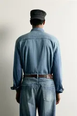 Camisa relaxed fit confeccionada en denim ligero de algodón, con cuello solapa, manga larga con puño abotonado, dos bolsillos de parche en el pecho con solapa y cierre frontal de botones. Presenta un efecto de lavado desgastado.