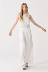 Conjunto de pantalón y top blancos de lino. El pantalón es de corte ancho con cintura elástica y bolsillos laterales. El top es sin mangas y de corte recto.