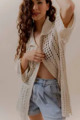 Saco calado negro tejido a máquina, con cuello tipo camisa y mangas 3/4.