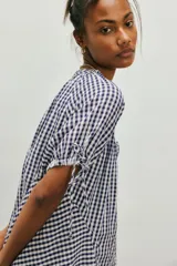 Túnica de algodón liviano con estampado de cuadros vichy en color azul marino y blanco. Presenta caída amplia y largo extendido, escote redondo con botonadura frontal y mangas cortas abullonadas con lazos ajustables.