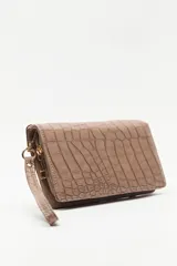 Billetera de mano con textura efecto cocodrilo, color beige, con cierre perimetral y tira de muñeca desmontable.