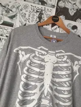 Remera gris con estampado de esqueleto en el frente.