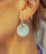 Aros de argolla plateados con dije circular de resina blanca rodeado de strass.