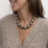 Collar de diseño artesanal compuesto por múltiples hileras de cuentas de resina pulida en una paleta de colores vibrantes que incluye tonos marrones, grises, verdes, naranjas y bordó.